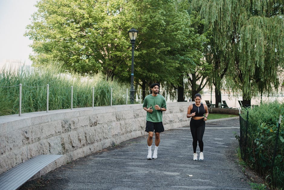 A man and woman jogging together in a lush, green park during the day